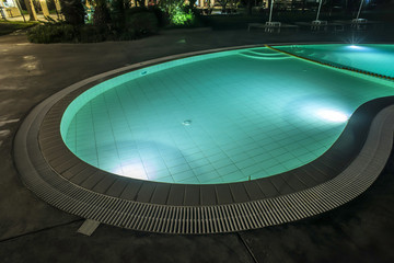Fototapeta na wymiar Pool, sunbeds and umbrellas at night