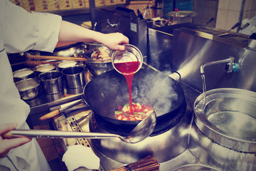 Chef is pouring sour sauce in wok, toned