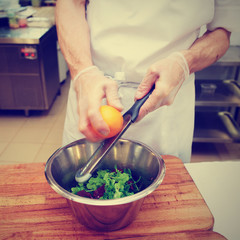 Chef is zesting orange in bowl with salad, toned