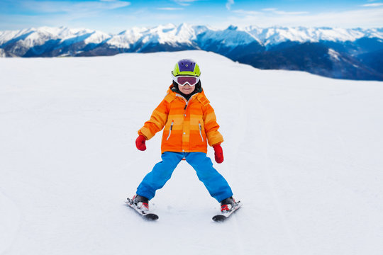 Boy wearing ski mask and helmet skiing on slope