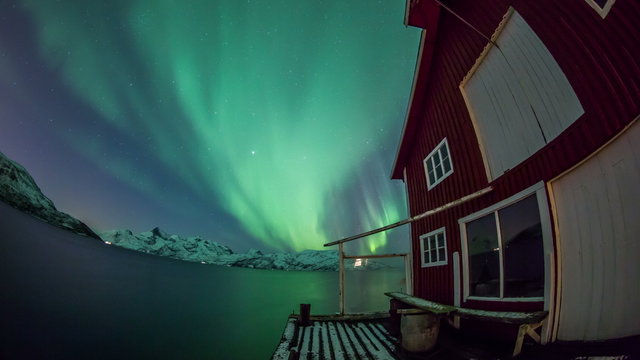 Aurora Borealis reflected on a lake with boat house