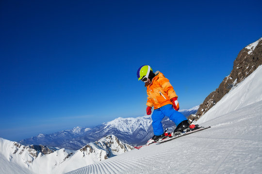 Brave small boy skiing alone on mountain slope