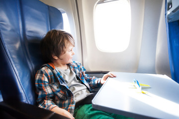 Happy boy sit in plane with toy model on table