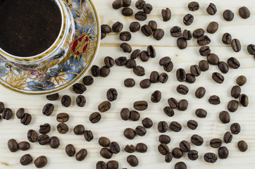 Porcelain coffee cup and coffee beans on wooden table