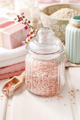 Fototapeta na wymiar Glass jar of pink sea salt on white wooden table