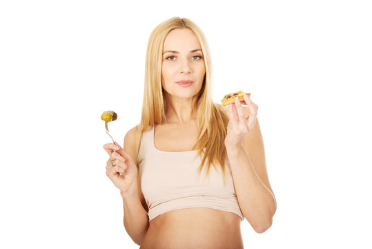 Happy pregnant woman with cake and pickles