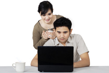 Couple enjoy coffee while using laptop