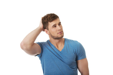 Young thoughtful man with hand behind head.