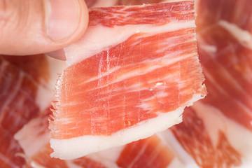 Top view of caucasian man hand taking Serrano ham slice