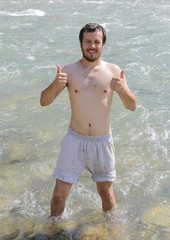man shows a sign of thumbs up after a swim in the icy mountain r