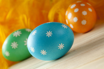 Easter eggs and feathers on wooden boards