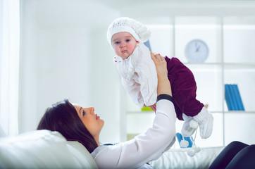 Young woman holding her baby in her arms in the living room