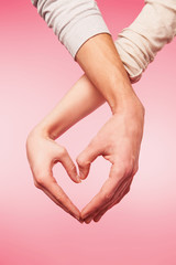 Closeup of woman and man hands showing heart shape