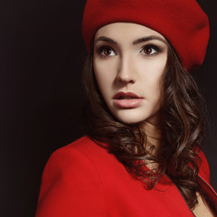 Stylish fashion girl in red suit and beret with, posing at studi