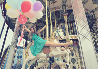 Merry-go-round young woman playing on carousel, toned.