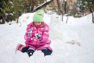 Fototapeta na wymiar Little blonde girl playing in the snow