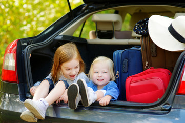 Two adorable little sisters sitting in a car