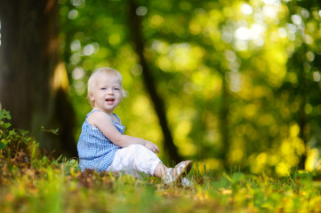 Cute toddler girl sitting on the grass on summer