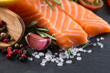 Portion of fresh salmon with spices,herbs and vegetables on blac