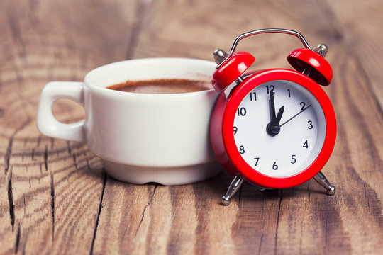 Cup of coffee with alarm clock