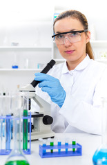 Fototapeta premium Woman working with a microscope in a lab