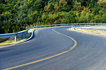 Asphalt road and green meadow and blue cloudy sky