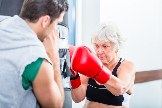 Seniorin Frau mit Trainer beim Boxen