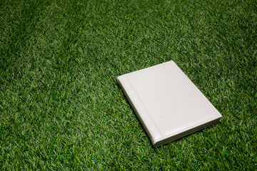 White leather book lying on the grass