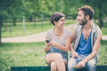 couple of friends young  man and woman using smartphone