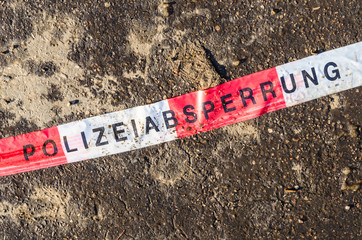 German police line red white tape on street asphalt dirt