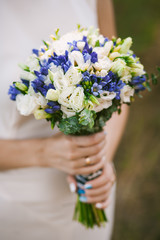 wedding bouquet of blue flowers in hands of bride