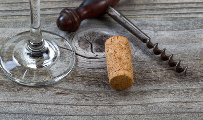 Used cork with corkscrew and wine glass in background on aged wo
