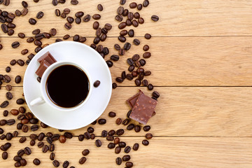 Cup of black coffee, chocolate and coffee beans on a wooden back
