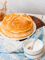 many thin sweet pancakes with honey on a wooden stand