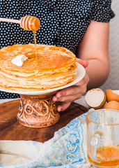 serve thin sweet pancakes on a wooden stand to pour honey, hands