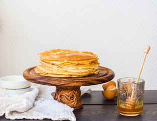 thin sweet pancakes with honey on a wooden stand, breakfast