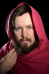 portrait of a bearded man in a studio in a red cape