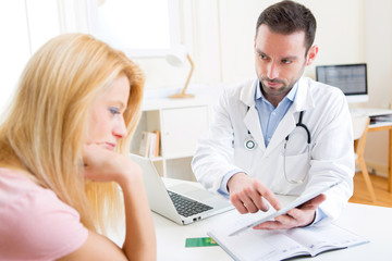 Young doctor showing results on tablet to patient