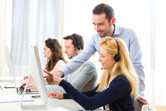 Manager training a young attractive people on computer