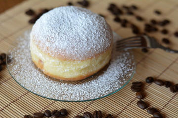 Delicious donut with icing sugar on plate on the table