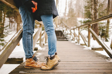 Hipster couple kissing on wooden stairs in winter park