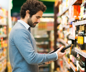 Man in a supermarket choosing a wine