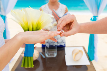 Groom giving an engagement ring to his bride under the arch deco