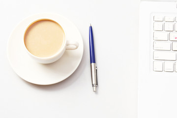 A cup of coffee and a pen near a laptop. Business concept.