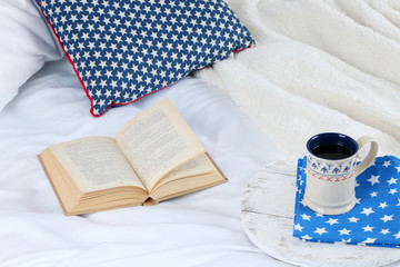 Book and cup of tea on bed close-up