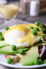 Toast with egg Benedict and avocado on plate on table close up