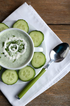 Cucumber soup in bowl on rustic wooden table background