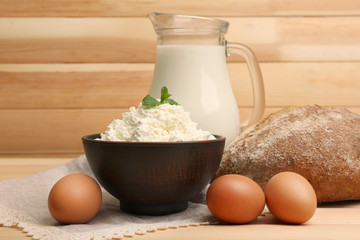 Cottage cheese in clay bowl with jug of milk, loaf of bread