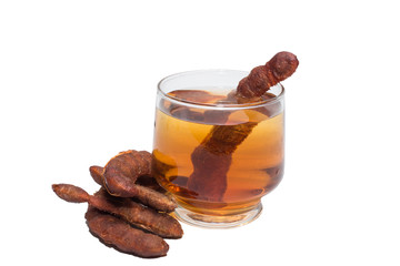 Tamarind juice in a glass surrounded by fresh ripe tamarinds