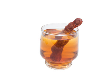Tamarind juice in a glass surrounded by fresh ripe tamarinds